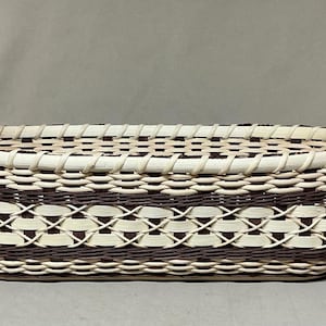 Peut inclure: Panier rectangulaire tissé avec des motifs bruns et crème. Il possède deux poignées en cuir marron. Le panier est fait de matériaux naturels et convient au rangement ou à l'exposition.