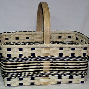 May include: A woven basket with a natural wood handle. The basket is made with white and dark blue woven strips. The basket is rectangular with rounded corners.