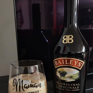 Peut inclure: Un verre de liqueur irlandaise à la crème avec des glaçons, étiqueté "Maman *Hors Service*" et une bouteille de liqueur irlandaise à la crème Baileys. La bouteille a une étiquette dorée avec le texte "The Original L'Originale Irish Cream - Crème Irlandaise" et un logo 88 doré.