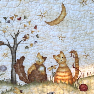 Peut inclure: Un panneau en tissu matelassé avec un fond crème et des motifs de surpiqûres en spirale. Le design présente un arbre aux feuilles en forme de cœur, un croissant de lune, des étoiles, deux chats dans l'herbe, une pelote de laine rouge et des fleurs jaunes.