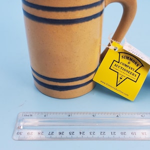 May include: A white ceramic mug with a black handle and the text "But first, coffee" in a handwritten style. The mug is on a white surface. The mug is likely for hot beverages.