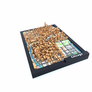 May include: A 3D model of Chicago, featuring a detailed cityscape with brown buildings and a map background. The model is set in a black frame, with the city's name printed on the side. The overall design is a unique representation of the city.