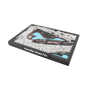 May include: A 3D map of the Australian Grand Prix circuit, featuring a black frame, white city details, a red track outline, and a light blue water feature. The text "Australian Grand Prix" is displayed on the front.