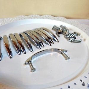 May include: A white ceramic mug with a black handle and the text "But First, Coffee" in a black, handwritten-style font. The mug is on a white surface.