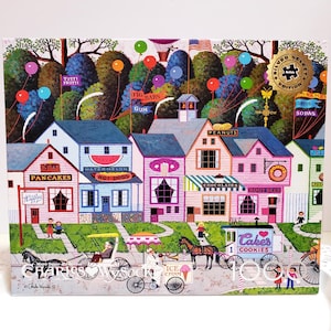 May include: A colorful jigsaw puzzle featuring a charming village scene with shops selling pancakes, hot dogs, and ice cream. The puzzle includes text such as "Tutti Frutti", "Fig Bars", and "Cakes". The image is a Silver Select Edition.