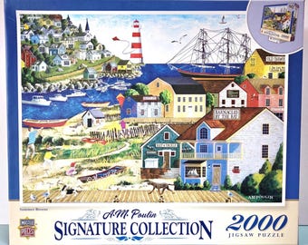 May include: A 2000-piece jigsaw puzzle by A.M. Poulin, featuring a colorful seaside town with a lighthouse, sailboats, and a wooden boardwalk. The puzzle box shows a detailed illustration of the scene, with the title "Summer Breeze" and the text "Signature Collection".