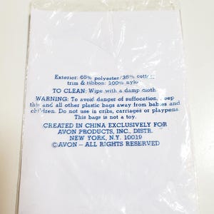 May include: A white paper insert with blue text inside a clear plastic bag. The text includes cleaning instructions, a warning about suffocation, and the phrase "CREATED IN CHINA EXCLUSIVELY FOR AVON PRODUCTS, INC."