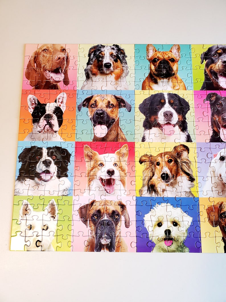May include: A colorful jigsaw puzzle featuring a grid of dog portraits. Each dog is set against a different vibrant background color, including pink, green, and blue. The dogs are of various breeds, with happy expressions.
