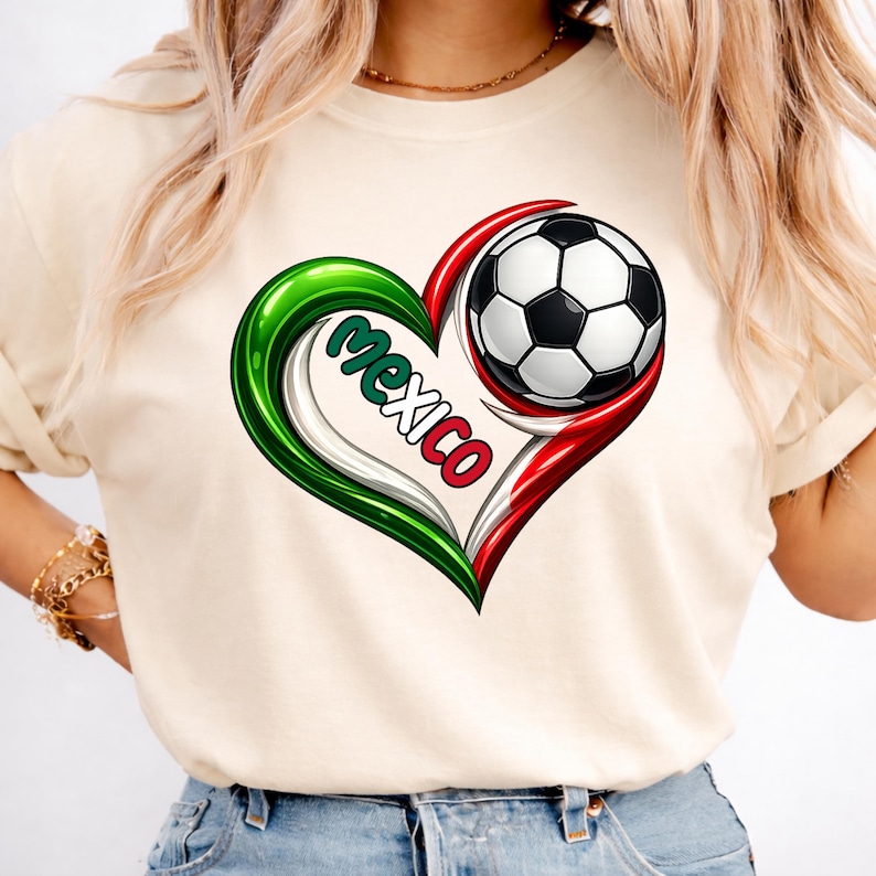 May include: A cream-colored t-shirt featuring a heart-shaped design in the colors of the Mexican flag. The design includes a soccer ball and the word "Mexico". The shirt is a casual style.