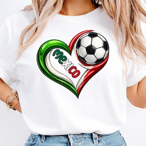 May include: White t-shirt featuring a heart-shaped design in the colors of the Mexican flag: green, white, and red. A soccer ball is nestled within the heart, and the word "Mexico" is written in the center.