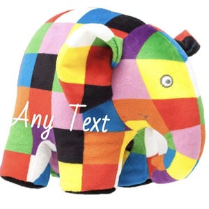 Pode incluir: Um brinquedo de pelúcia de elefante com um design de retalhos de cores vibrantes, incluindo vermelho, azul, amarelo e verde. O brinquedo tem uma tromba, orelhas e uma pequena cauda. O texto "Any Text" está escrito no corpo do elefante.