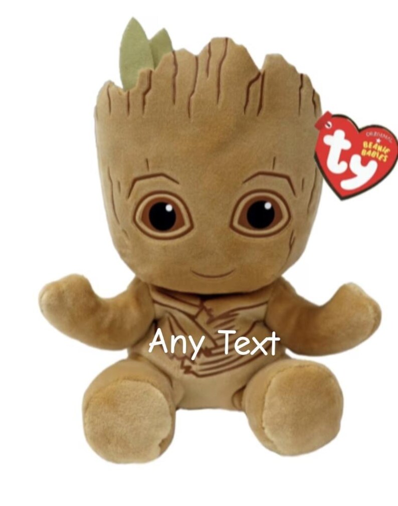 May include: A plush toy of a character with a tree-like appearance, featuring a brown body, large eyes, and small green leaves. The toy has the text "Any Text" and a red heart-shaped tag.