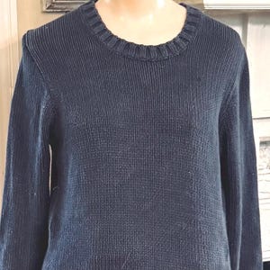 May include: A navy blue ribbed knit sweater with a crew neck. The long-sleeved sweater has a textured appearance and a classic design. The neckline and cuffs have a ribbed detail. This versatile sweater is suitable for various occasions.