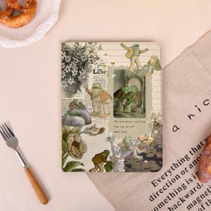 Könnte beinhalten: Ein rechteckiges Notizbuch mit einer Collage aus Illustrationen von Fröschen und Kröten in verschiedenen Szenen, darunter eine vor einem Spiegel. Der Text lautet: "We look brave," said Frog. "Yes, but are we?" asked Toad. Der Einband ist beige.