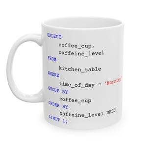 May include: White ceramic coffee mug featuring a black and blue text design, resembling a code snippet. The text includes "SELECT", "FROM", "WHERE", and "Morning". The mug has a curved handle and is suitable for hot drinks.
