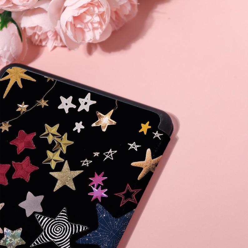 May include: Black phone case with a colorful star design. The case features various star shapes in gold, red, white, and other colors. The stars are scattered across the black surface, creating a celestial theme.