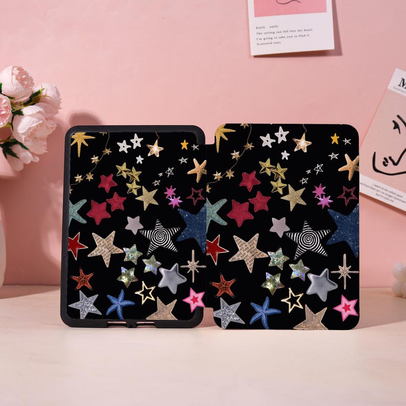 May include: Black tablet case with a colorful star pattern. The design features various star shapes in gold, silver, red, blue, and pink. The case is rectangular and has a black border.