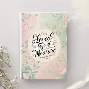 Può includere: Un taccuino con un design floreale. La copertina presenta le parole "Loved beyond Measure" in una scrittura elegante all'interno di una cornice circolare. Sfondo acquerello rosa e verde chiaro con accenti floreali.