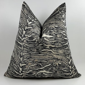 May include: A decorative throw pillow with a black, white, and gray zebra stripe pattern. The pillow has a soft, textured appearance and is designed to add a touch of style to any room. The pillow is square-shaped.