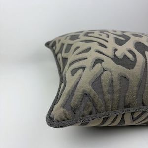 Cuscino boho in ciniglia intrecciata grigio scuro con motivo e bordino.