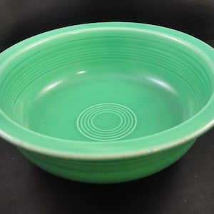 May include: A green ceramic bowl with a fluted rim and a concentric circle design in the center.