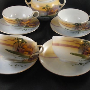 May include: A vintage tea set with a cream-colored base and a delicate floral design. The set includes a teapot, four cups, and four saucers.