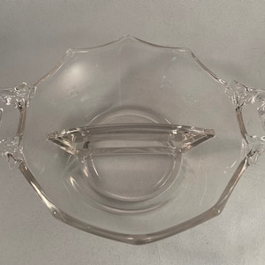 May include: A clear glass divided serving dish with two handles. The dish has a central divider that separates the two sections.