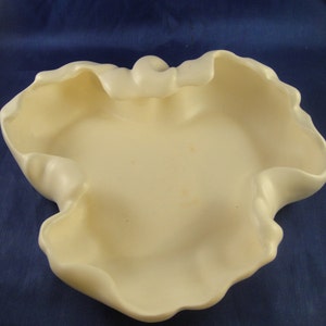 May include: A white ceramic bowl with a unique, organic shape. The bowl has a smooth, rounded surface and a wide, open rim.