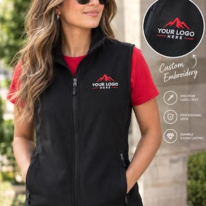 Può includere: Un gilet nero con cerniera, caratterizzato da una grafica di montagna rossa e dal testo YOUR LOGO HERE ricamato sul petto sinistro. Il gilet include una chiusura frontale a zip, un colletto alto e due tasche laterali con zip, indossato sopra una t-shirt rossa.