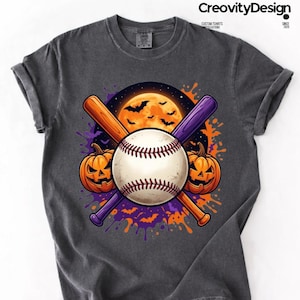 May include: A charcoal grey t-shirt featuring a graphic of a white baseball centred over two crossed baseball bats, one orange and one purple. Two orange jack-o'-lanterns flank the ball against a background of a full moon and flying bats.