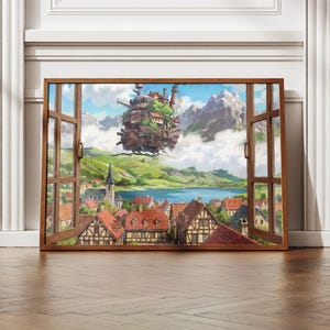 May include: A framed print showing a fantastical landscape seen through an open window. The artwork features a floating castle above a village with red roofs, a lake, and mountains. The frame is brown, set against a white wall and a wooden floor.