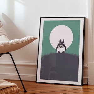 Może przedstawiać: Oprawiony wydruk artystyczny przedstawiający postać z kresk&oacute;wki z dużym białym księżycem w tle. Grafika, w czarnej ramie, opiera się o białą ścianę. Kolorystyka obejmuje odcienie zieleni, szarości i bieli.