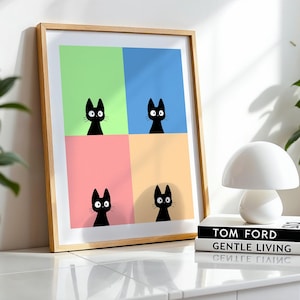 May include: A framed art print featuring four black cat silhouettes against a colorful background of green, blue, pink, and yellow. The artwork is displayed on a white surface next to a white mushroom-shaped lamp and two books.