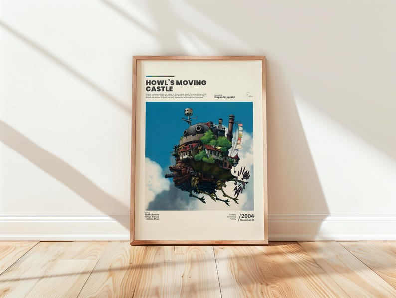 May include: Framed poster featuring the text "Howl's Moving Castle" above an illustration of the castle in the sky. The artwork depicts a whimsical, multi-layered structure with a blue sky and white clouds in the background. The poster is in a wooden frame.