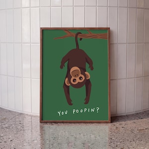 Può includere: Una stampa artistica rettangolare incorniciata raffigurante una scimmia marrone scuro appesa a testa in giù a un ramo di un albero marrone su uno sfondo verde scuro a tinta unita. Il testo "YOU POOPIN?" è stampato in maiuscolo bianco in basso.