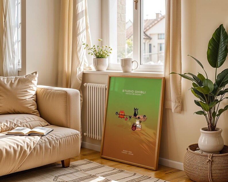 May include: A framed Studio Ghibli poster with a green and orange gradient background. The poster features cartoon characters and the text "STUDIO GHIBLI" and "SINCE 1985 TOKYO - JAPAN". The poster is leaning against a wall near a window.