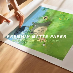May include: A rolled-up white poster and a printed poster featuring a scene from a Studio Ghibli film. The poster has a green and blue background with the text "PREMIUM MATTE PAPER" and "POSTERS FOR UP TO 40% OFF".