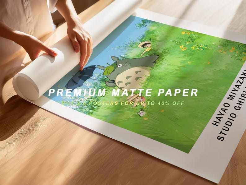May include: A rolled-up white poster and a printed poster featuring a scene from a Studio Ghibli film. The poster has a green and blue background with the text "PREMIUM MATTE PAPER" and "POSTERS FOR UP TO 40% OFF".
