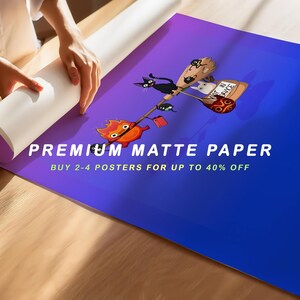 May include: A rolled-up poster with a gradient blue and purple background. The poster features a cartoon illustration of a black cat, a white cat, and a fiery creature riding a broom. Text on the poster reads "PREMIUM MATTE PAPER".