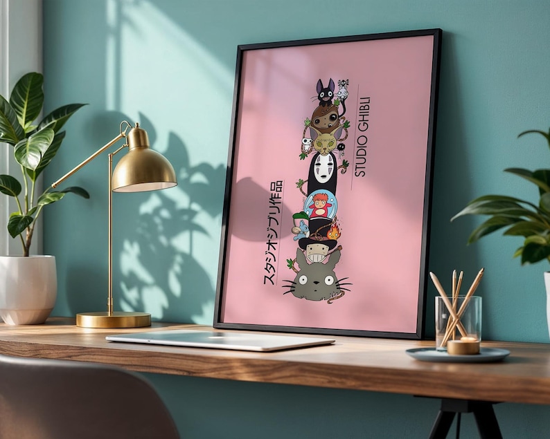 Puede incluir: Un p&oacute;ster enmarcado con fondo rosa, que muestra personajes de Studio Ghibli apilados verticalmente. El marco negro rodea la obra de arte, que incluye personajes como Totoro y Sin Rostro. Texto japon&eacute;s visible a la izquierda, con "STUDIO GHIBLI" a la derecha.