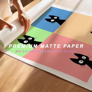 May include: A rolled-up poster featuring a repeating pattern of black cat faces on a colorful background. The poster has text that reads "PREMIUM MATTE PAPER" and "BUY 2-4 POSTERS FOR UP TO 40% OFF". The background colors are blue, green, peach, and pink.