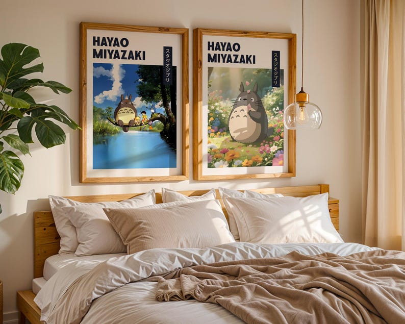 May include: Two framed art prints featuring Hayao Miyazaki illustrations. One shows a scene with characters on a tree branch over water, the other depicts a character in a field of flowers. Both have wooden frames.