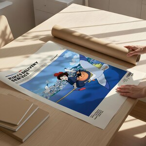 Puede incluir: Un p&oacute;ster de "Nicky, la aprendiz de bruja" con el texto del t&iacute;tulo. La obra de arte representa a una joven volando en una escoba sobre un cielo azul. Tambi&eacute;n se ve un tubo de papel marr&oacute;n enrollado y varios cuadernos cuadrados marrones.