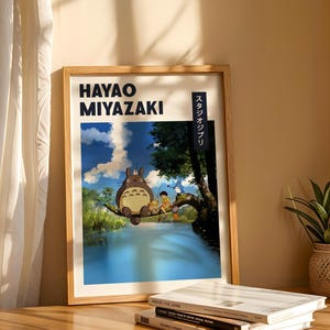 May include: A framed poster featuring Hayao Miyazaki artwork. The poster depicts a scene with a large, furry creature and two children near a body of water. The text "HAYAO MIYAZAKI" is at the top, with Japanese text on the right side.
