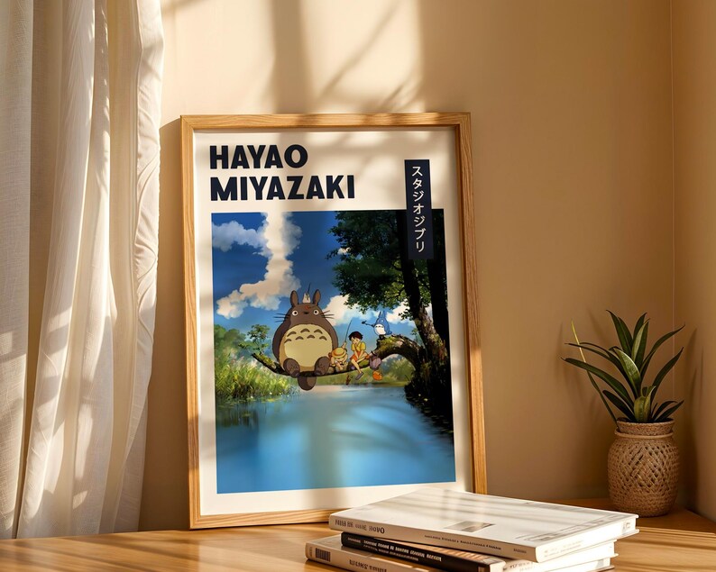 May include: A framed poster featuring Hayao Miyazaki artwork. The poster depicts a scene with a large, furry creature and two children near a body of water. The text "HAYAO MIYAZAKI" is at the top, with Japanese text on the right side.