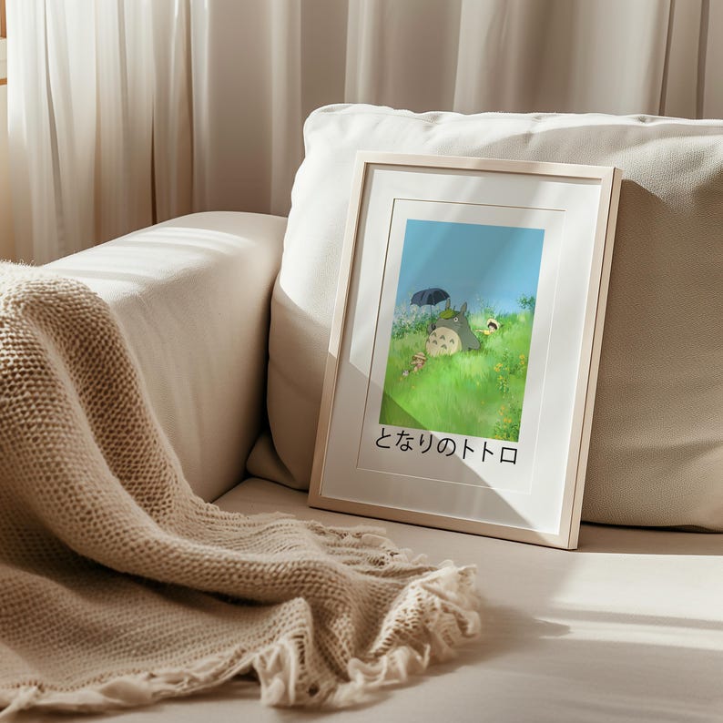 May include: A framed print featuring a scene from the animated film "My Neighbor Totoro." The artwork depicts Totoro and other characters in a grassy field under a blue sky. The Japanese title is displayed at the bottom.