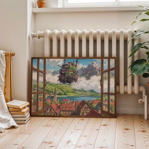 May include: A framed artwork showing a fantasy landscape through an open window. It features a floating castle, a village with red-tiled roofs, mountains, and a lake. The artwork is on a wooden floor, next to a plant in a terracotta pot.