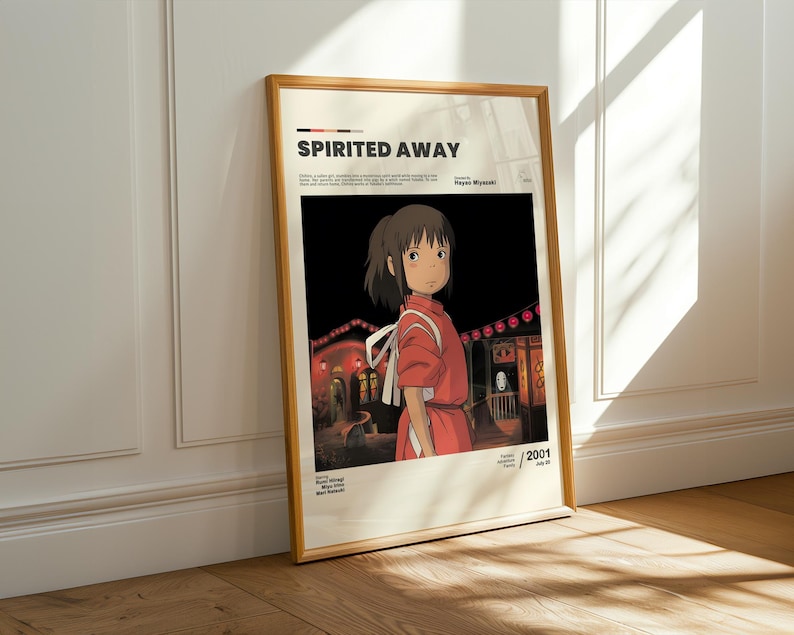 May include: Framed poster featuring the animated film "Spirited Away." The artwork depicts a young girl in a red outfit, set against a backdrop of traditional Japanese buildings illuminated at night. The poster has a wooden frame.