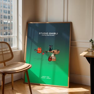 May include: A framed poster featuring a Studio Ghibli design with a green and blue gradient background. The poster includes illustrations of animated characters and the text "STUDIO GHIBLI - HAYAO MIYAZAKI" and "SINCE 1985 TOKYO - JAPAN."