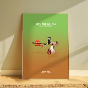 May include: A framed poster with a gradient green and orange background. The poster features Studio Ghibli characters, including a black cat, a white cat, and a red owl-like creature. Text at the top reads "STUDIO GHIBLI - HAYAO MIYAZAKI-" and at the bottom "SINCE 1985 TOKYO - JAPAN."